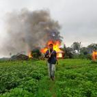 10 junio 2012 Un hombre de la etnia rahkine camina llevando armas de fabricación casera, dejando a sus espaldas una casa recién incendiada durante los enfrentamientos entre budistas y musulmanes de la comunidad rohingya in Sittwe, Birmania.