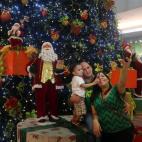 5Una familia se toma una fotografía en el Agora Mall en Santo Domingo (República Dominicana). Los dominicanos abarrotan las tiendas y supermercados horas antes de la Nochebuena en medio de un amplio operativo de seguridad montado por las autor...