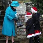 La reina Isabel II de Inglaterra recibe unas flores a manos de unas niñas vestidas de forma navideña a la salida de la misa a la que acude tradicionalmente la familia real británica el día de Navidad.