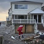En esta foto del martes 18 de diciembre de 2012, el consultor político Michael Sciaraffo, disfrazado de Santa Claus, lleva juguetes a hogares afectados por el huracán Sandy en el barrio Bell Harbor de Nueva York. Los cambios climáticos que se...