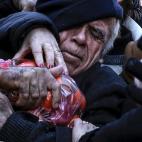 Enero de 2016. Un hombre se abraza a una bolsa de mandarinas en una entrega de productos gratuitos realizada por agricultores griegos durante una protesta contra la reforma de las pensiones en Atenas (Grecia).