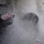 Enero de 2013. Rebeldes sirios se cubren mientras el muro que les proteg&iacute;a es golpeado por munici&oacute;n disparada desde el Ej&eacute;rcito sirio en Damasco (Siria).