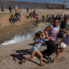 Noviembre de 2018. Una mujer de Honduras corre junto a sus hijas huyendo de los gases lanzados por la Polic&iacute;a en la frontera entre EEUU y M&eacute;xico en Tijuana (M&eacute;xico).