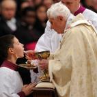 Pope Benedict XVI (R) gives the communion to an altar boy as he celebrates Christmas mass at St. Peter's Basilica in Vatican City on December 24, 2011, to mark the nativity of Jesus Christ. Pope Benedict XVI hailed Christ's humility, urging the ...