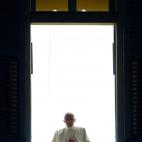 Pope Benedict XVI lights a candle in his private window, at the end of the unveiling ceremony of the crib in St Peter's Square at the Vatican, on December 24, 2011. Pope Benedict XVI will celebrate late Christmas night holy mass at St. Peter's B...
