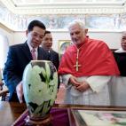 Pope Benedict XVI looks at a gift offered by Vietnam's President Nguyen Minh Triet (L) during their meeting in his private library at the Vatican on December 11, 2009. AFP PHOTO / CHRISTOPHE SIMON (Photo credit should read CHRISTOPHE SIMON/AFP...