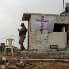 Un soldado iraqu&iacute; monta guardia en una garita con la cruz cristiana.