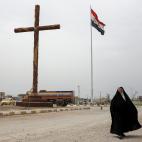 Una mujer camina junto a una gran cruz levantada nuevamente en la ciudad.