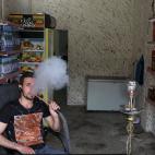 Steve Ibrahim, un cristiano que regenta una tienda de venta de alcohol, fuma en su local de la localidad iraqu&iacute;.