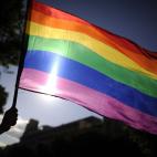 Una persona sostiene una bandera arcoíris en las calles de Madrid.