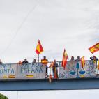 Un grupo de personas ondean banderas de España al paso de la marcha convocada por los CDR que camina desde Casteldefels hacia Barcelona para unirse a las otras cinco "Marchas por la Libertad" que confluyen este viernes en la capital catalana