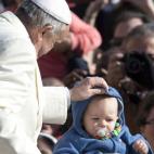 ALTERNATIVE CROP OF AJM103 Pope Francis adjusts a baby's hood as he arrives for his weekly general audience, in St. Peter's Square, at the Vatican, Wednesday, Feb. 18, 2015. (AP Photo/Andrew Medichini)