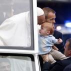 Pope Francis holds the head of a baby as he stands in the popemobile during a parade on the Benjamin Franklin Parkway, Sunday, Sept. 27, 2015 in Philadelphia. The pope will end the final day of his three-city U.S. tour with a Mass on Philadelphi...