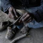 Ali, de Camerún, arregla una suela de zapato en su escondite.