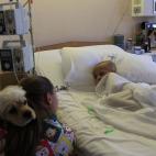 Dana de siete años está acostada en la cama de un hospital en Quito, Ecuador, junto a la voluntaria Veronica Pardo, quien carga a su perro Lancelot.
