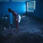 Ibrahim Fambulle, apenas capaz de ponerse de pie, trata de caminar por una sala de aislamiento en Monrovia, Liberia. Las personas sospechosas de tener el virus del Ébola son enviadas a este centro, una escuela primaria cerrada.