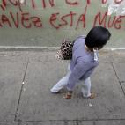 Una mujer camina por una calle de Caracas, donde se puede leer "Chávez está muerto" en relación con las especulaciones de la gravedad del presidente venezolano, quien se encuentra hospitalizado en Cuba.