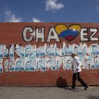 Una mujer pasa frente a un muro con carteles de la campaña de reelección del presidente venezolano Hugo Chávez en Caracas, Venezuela, el miércoles 9 de enero de 2013. El gobierno de Obama espera que el posible fin del gobierno de 14 años de...