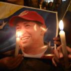 Un poster de Hugo Chávez en medio de la concentración de gente que se acercó a la embajada de Venezuela en Quito, tras conocer anunciarse su fallecimiento.