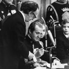 Juan Carlos I firma la Constituci&oacute;n Espa&ntilde;ola de 1978 en el Congreso en Madrid. A su izquierda, Antonio Hern&aacute;ndez Gil, presidente de las Cortes.