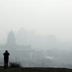 A man stops to take a picture of the Utah State Capitol (L) and buildings that are shrouded in smog in downtown Salt Lake City, Utah, U.S. December 12, 2017. Sometimes during the winter, temperature inversions form in the Salt Lake Valley, when ...