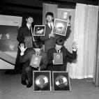 The Beatles, pictured at EMI House Manchester Square, London, with a hoard of silver discs. They were presented with two silver LPs to mark the quarter-million plus sales of their first LP &quot;Please Please Me&quot; and their new one &quot;Wit...