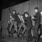 The Beatles jump on stage, left to right, Paul McCartney, Ringo Starr, John Lennon, and George Harrison.