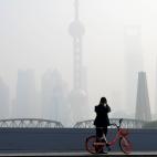A man takes picture on a bridge in front of the financial district of Pudong covered in smog during a polluted day in Shanghai, China November 28, 2018. REUTERS/Aly Song