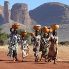 Mujeres de la tribu peul en Mali portan sobre sus cabezas grandes cuencos con ropa y leche.