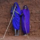 El vivo color azul de las togas de los jóvenes suris resalta ante el agrietado muro de adobe en en el valle del Omo, Etiopía.