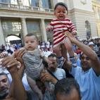 Varios migrantes alzan a sus bebés ante las cámaras.