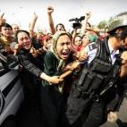 Dos mujeres de la etnia uygur agarran el brazo a un policía antidisturbios en una protesta en Urumqi, en la provincia occidental de Xinjiang el 7 de julio de 2009. La Policía lanzó gases lacrimógenos para dispersar a los miles de manifestant...