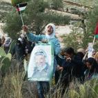 Una estudiante musulmana enseña una imagen del líder palestino Yasser Arafat y una bandera nacional entre los cientos de mujeres que protestan por la construcción de la conflictiva valla israelí el 1 de enero de 2004.
