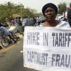 Una mujer muestra una pancarta que pone "El aumento de tarifas es fraude capitalista" durante una protesta por la subida de un 45% del precio de la electricidad el 8 de febrero de 2016 en Lagos.