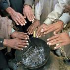 Refugiados del campamento ubicado en el pueblo de Bateela, en Pakistán, se juntan para calentar sus manos en una hoguera común.