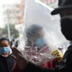Una mujer se protege con una m&aacute;scara y hasta con una bolsa en la provincia de Hubei