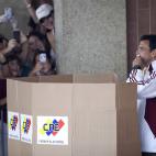 Opposition presidential candidate Henrique Capriles kisses his ballot before voting at a polling station as voters take pictures of him in Caracas, Venezuela, Sunday, April 14, 2013. Capriles is running for president against Nicolas Maduro, the ...
