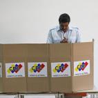 Venezuela's interim President Nicolas Maduro stands behind the voting booth as he votes in the presidential election at a polling station in Caracas, Venezuela, Sunday, April 14, 2013. Maduro, who served as late President Hugo Chavez's foreign m...