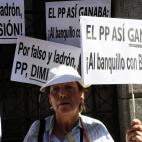 Una señora sostiene pancartas acusatorias contra el extesorero del PP.
