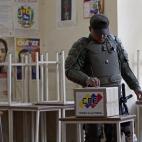 A soldier wearing protective gear casts his ballot during the presidential election at a polling station in Caracas, Venezuela, Sunday, April 14, 2013. Interim President Nicolas Maduro, who served as the late President Hugo Chavez's foreign mini...