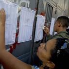 Residents look for their name on the voters list outside a polling station to vote in presidential elections in Caracas, Venezuela, early Sunday, April 14, 2013. Interim President Nicolas Maduro, who served as late President Hugo Chavez's foreig...