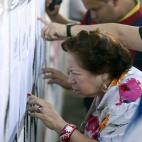 Residents look for their names on voters lists outside a polling station during the presidential election in Caracas, Venezuela, early Sunday, April 14, 2013. Interim President Nicolas Maduro, who served as the late Hugo Chavez's foreign ministe...