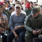 A soldier wearing protective gear waits with civilians to cast his vote in the presidential election at a polling station in Caracas, Venezuela, Sunday, April 14, 2013. Interim President Nicolas Maduro, who served as the late Hugo Chavez's forei...