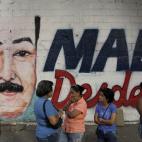 Residents wait to enter a polling station where a nearby wall is covered with a mural of interim President Nicolas Maduro during the presidential election in Caracas, Venezuela, early Sunday, April 14, 2013. Interim President Nicolas Maduro, who...