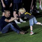 Barcelona's coach Josep Guardiola plays with a child while celebrating at Nou Camp stadium in Barcelona on May 13, 2011, after winning the Spanish League title. Barcelona were crowned Spanish champions for the third successive season with a 1-1 ...