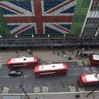 Peatones caminan por Oxford Street donde se ha colocado una bandera británica en la fachada de unos grnades almacenes en Londres