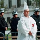 Un miembro del Ku Klux Klan posa arrogante tras una barrera policial para su protecci&oacute;n durante una marcha en Nueva York en 1999.
