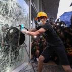 Un manifestante intenta romper una cristalera del Consejo Legislativo en Hong Kong (China)
