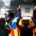 Un hombre porta una urna junto a otro con una bandera independentista catalana