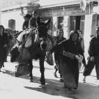 Una mujer conduce una mula con sus pertenencias por las calles de Le Perthus durante la Guerra Civil en 1939.